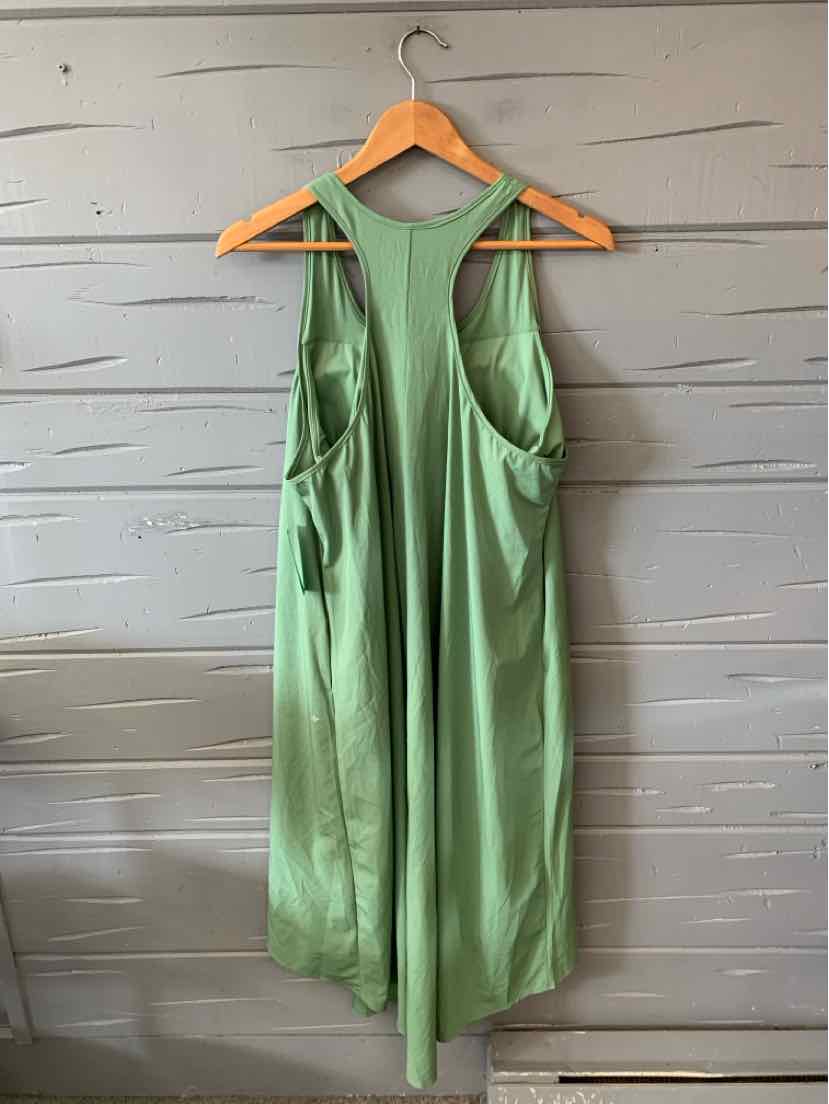 Light green sleeveless jumpsuit with wide leg pants, scoop neckline, and side pockets hanging on wooden hanger.