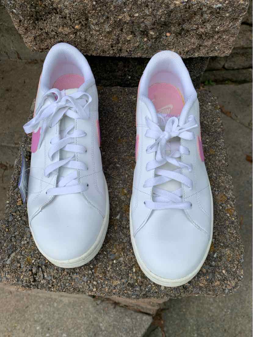 Pair of white Nike sneakers with lace-up fronts, pastel pink and blue lining, and textured rubber soles.