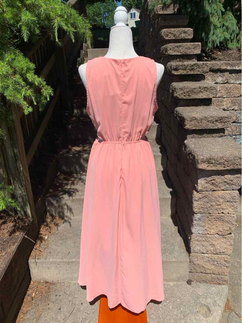 Sleeveless coral pink midi dress with cinched waist and soft fabric on mannequin outdoors.