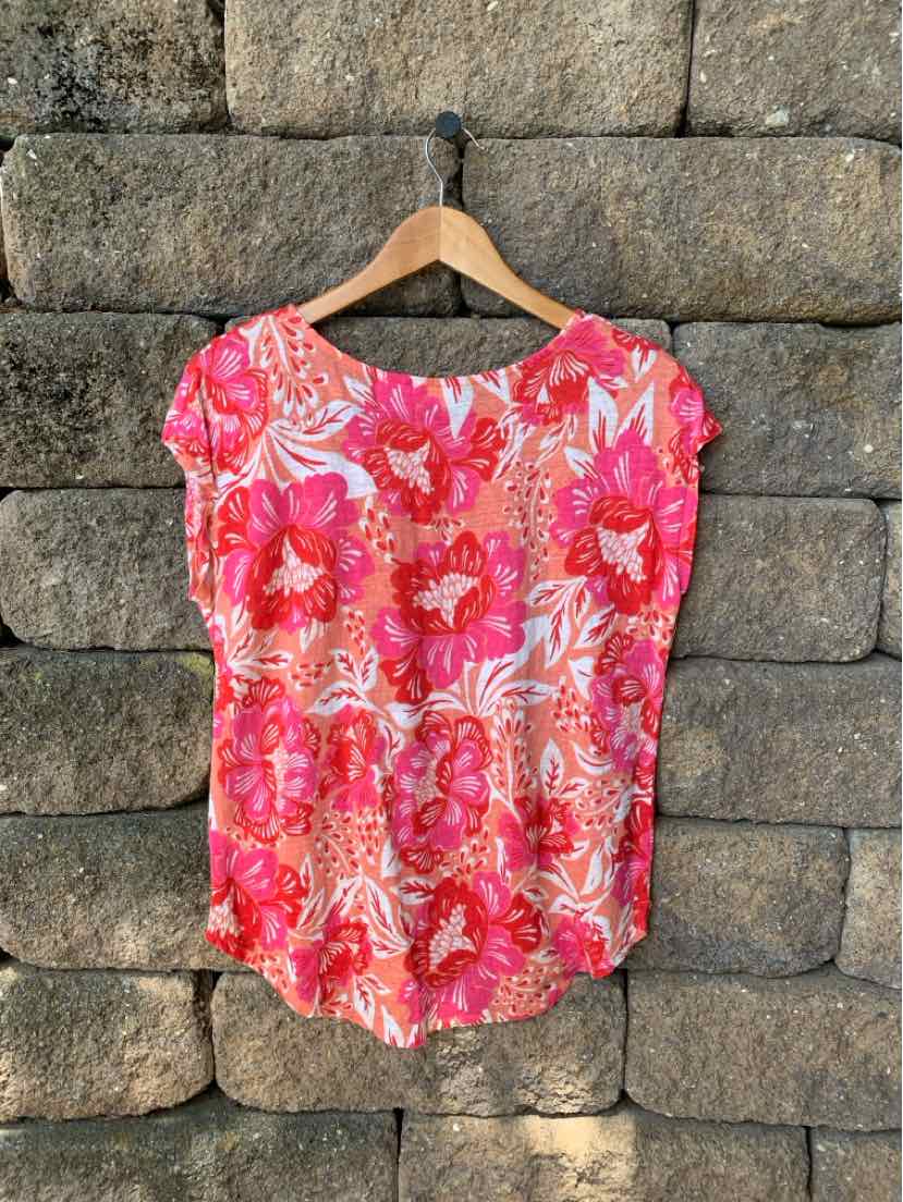 Pink floral short-sleeve blouse with round neckline and relaxed fit on wooden hanger.