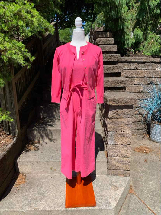 Pink long-sleeve jumpsuit with tie waist and front keyhole neckline on mannequin outdoors.