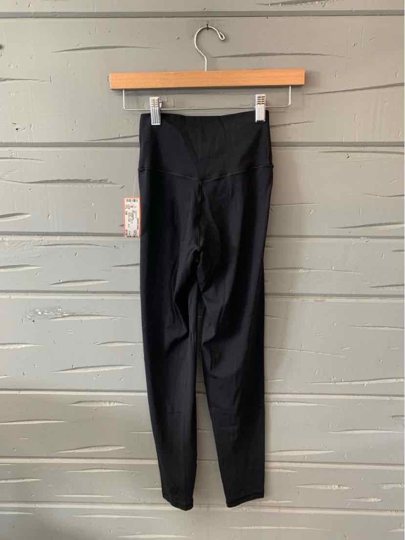 Black high-waisted leggings with a smooth finish, ankle length, and a tag on the left side.