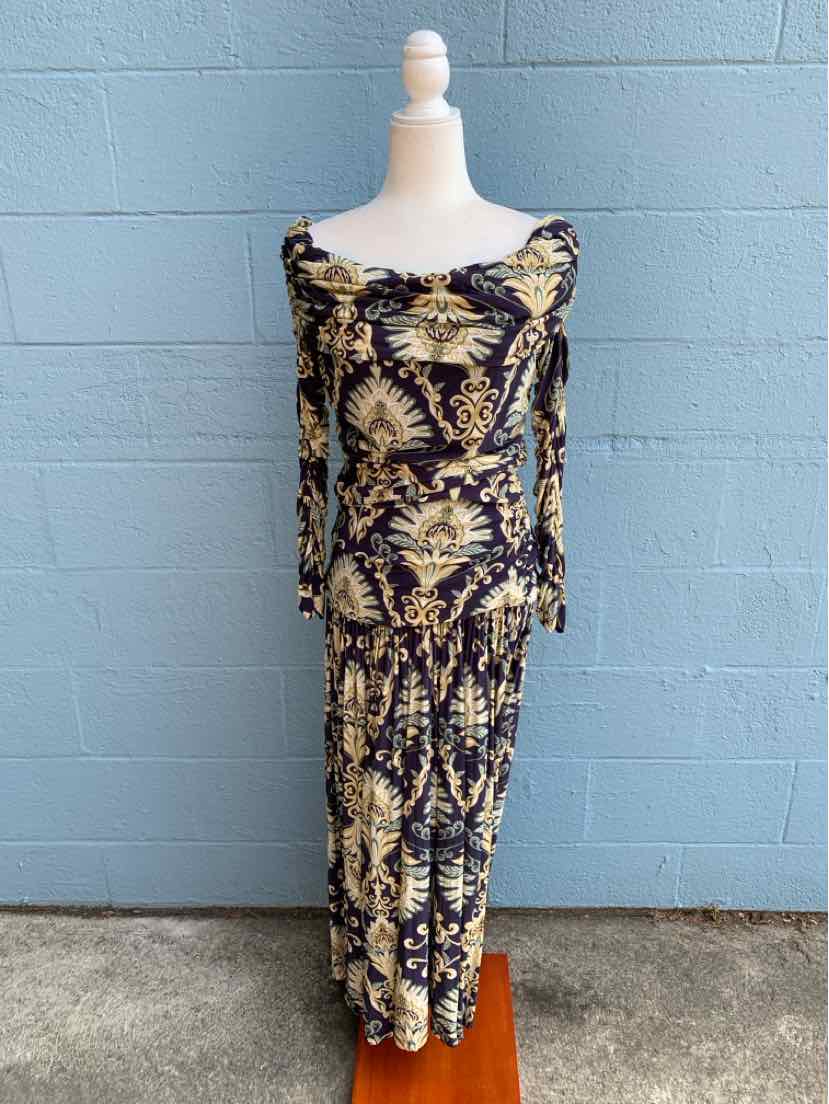 Long fitted dress with a navy base and intricate gold and cream tropical leaf pattern, featuring long sleeves and a boat.