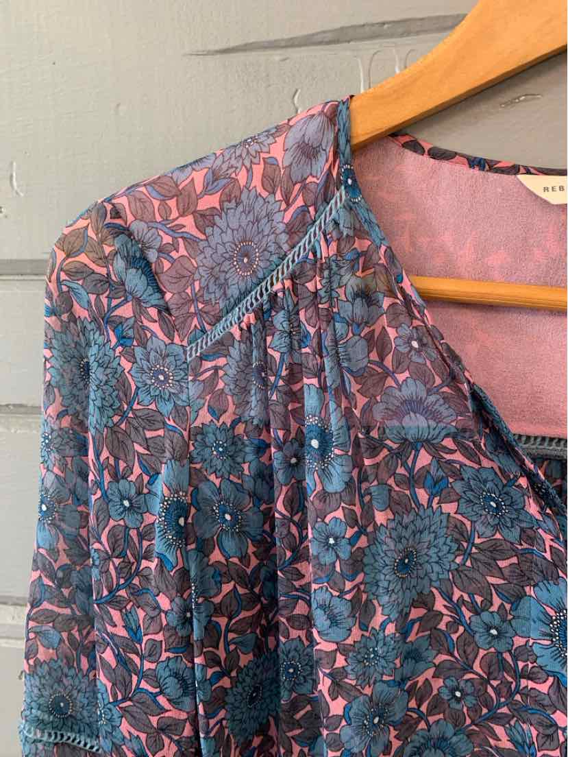 Blue and pink floral blouse with gathered yoke and scoop neckline on wooden hanger.