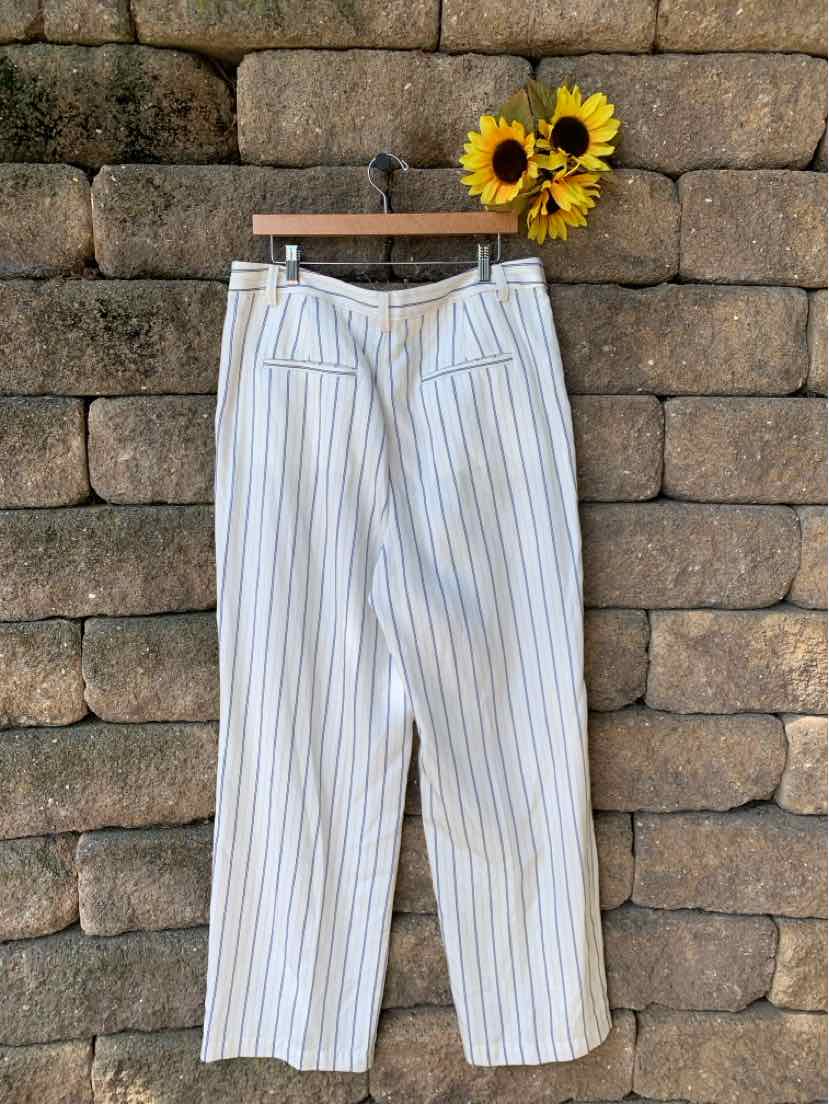 White wide-leg pants with vertical black stripes, high waist, and front pockets, hanging on wooden hanger.