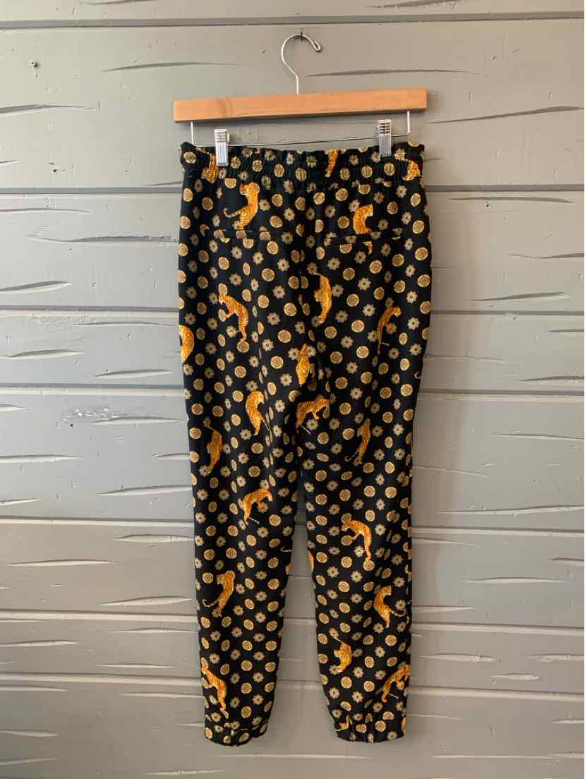 Black tapered pants with an elastic waist and ankles, featuring an orange tiger and circular pattern.