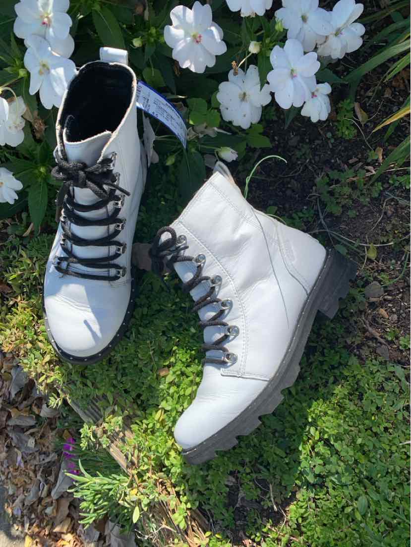Pair of white leather SOREL ankle boots with black laces, metal eyelets, and chunky dark soles.