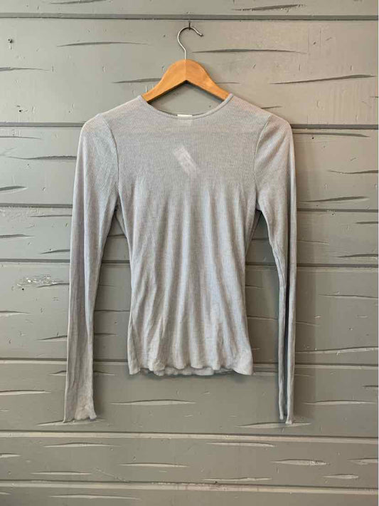 Light gray long-sleeve slim-fit crewneck shirt with subtle ribbed texture on wooden hanger.