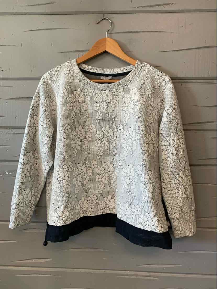 Light gray jacquard long-sleeve sweater with floral texture and black hem layer detail.