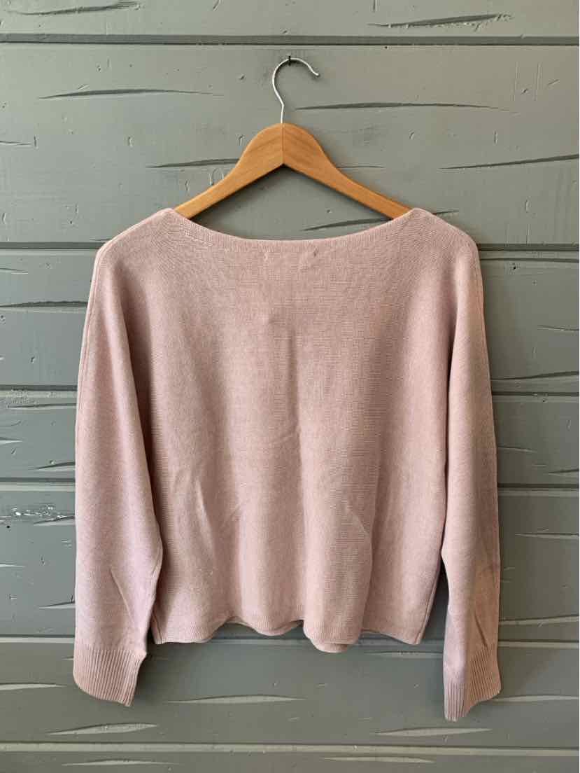 Mauve knit sweater with long sleeves and a wide neckline on wooden hanger against gray wall.