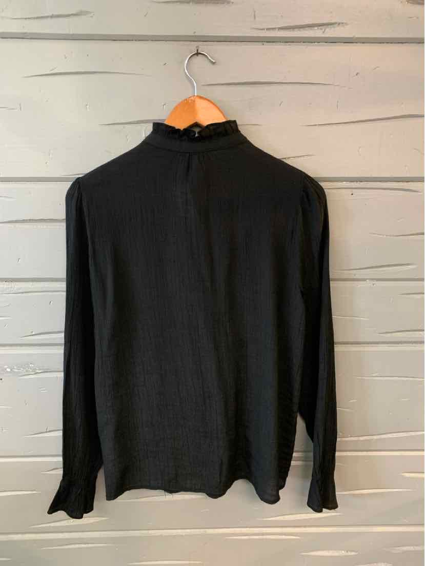 Black long-sleeve ribbed top with mock neck on wooden hanger against grey wall.