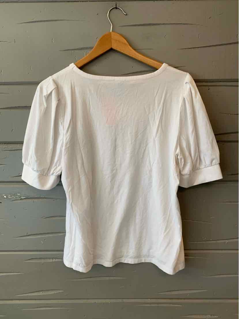 White blouse with puffed elbow-length sleeves and boat neckline on wooden hanger.