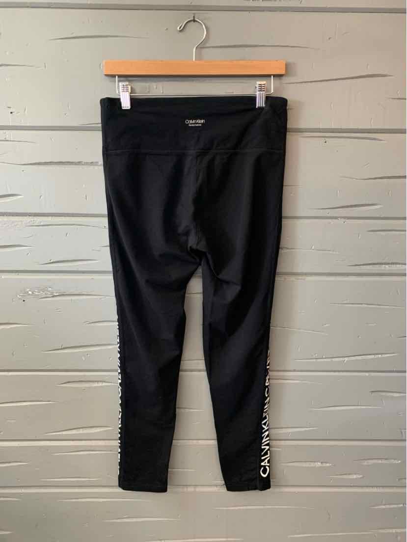 Black Calvin Klein leggings with high waistband and white logo text along the lower leg.