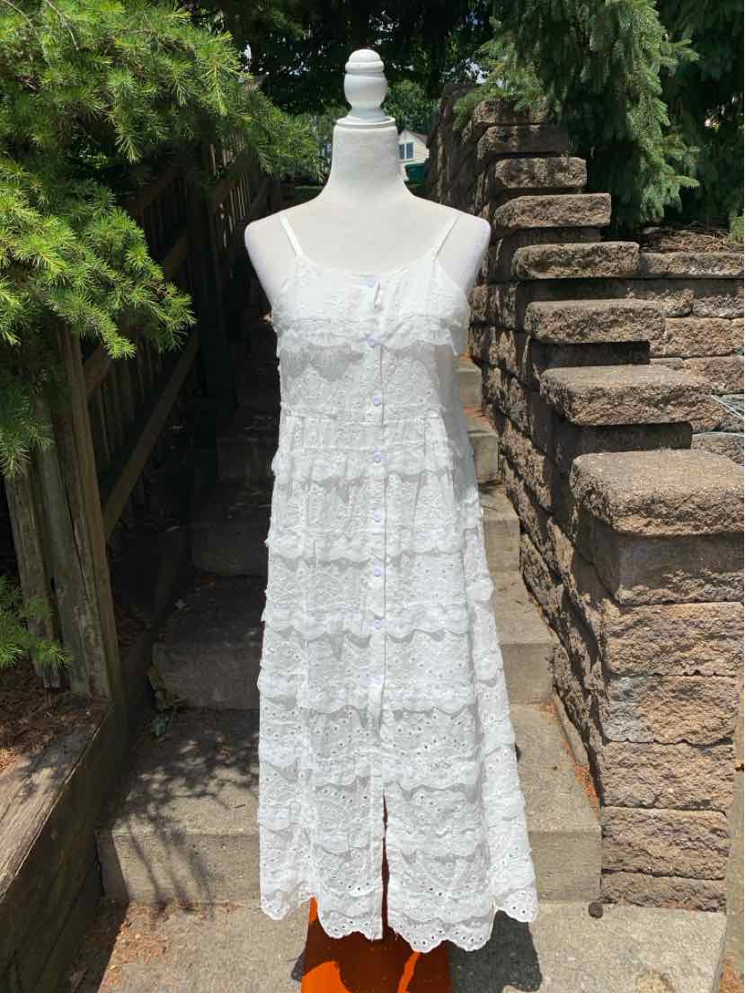 White sleeveless eyelet midi dress with tiered ruffles and front slit.
