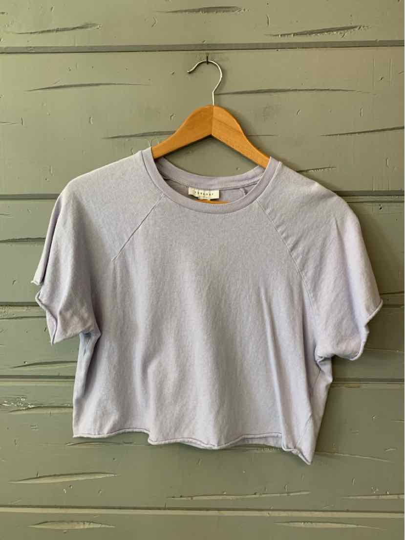 Lavender short-sleeve cotton T-shirt with crew neck and relaxed fit hanging on wooden hanger.