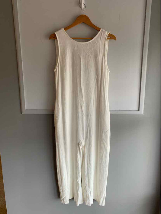 White sleeveless jumpsuit with wide legs and round neckline hanging on wooden hanger.