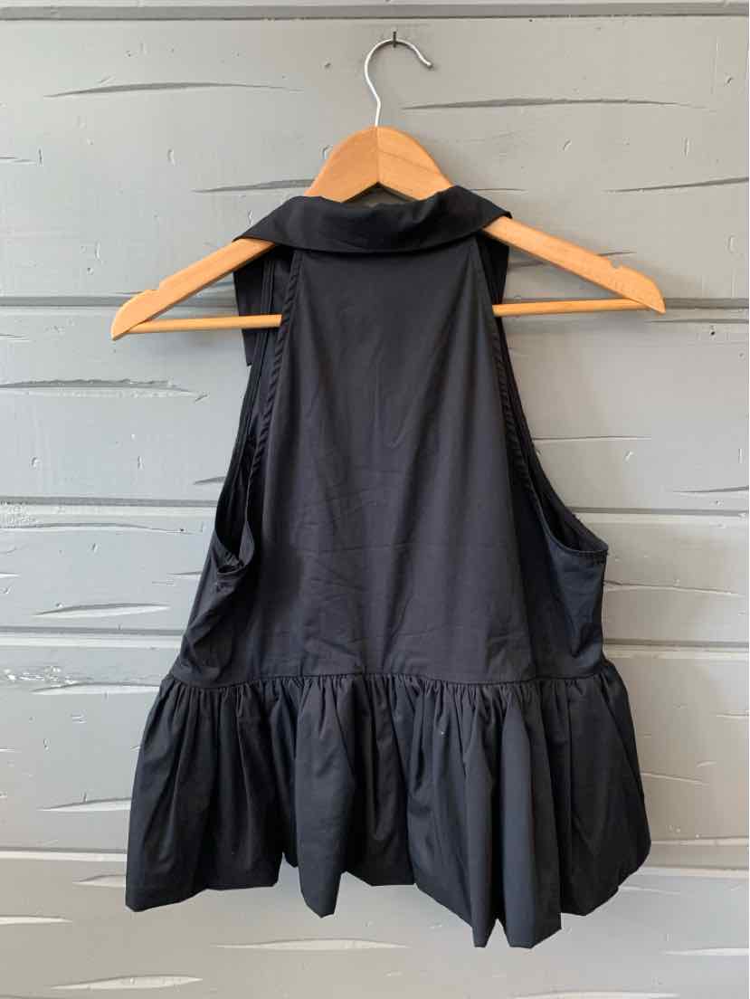 Black sleeveless top with ruffled hem and high neckline on wooden hanger.