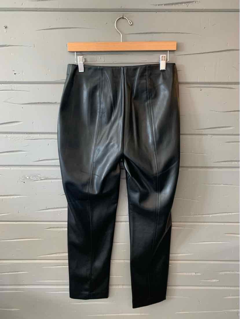 Black faux leather slim-fit pants with a tapered leg and clean back seams, hanging on a wooden hanger.
