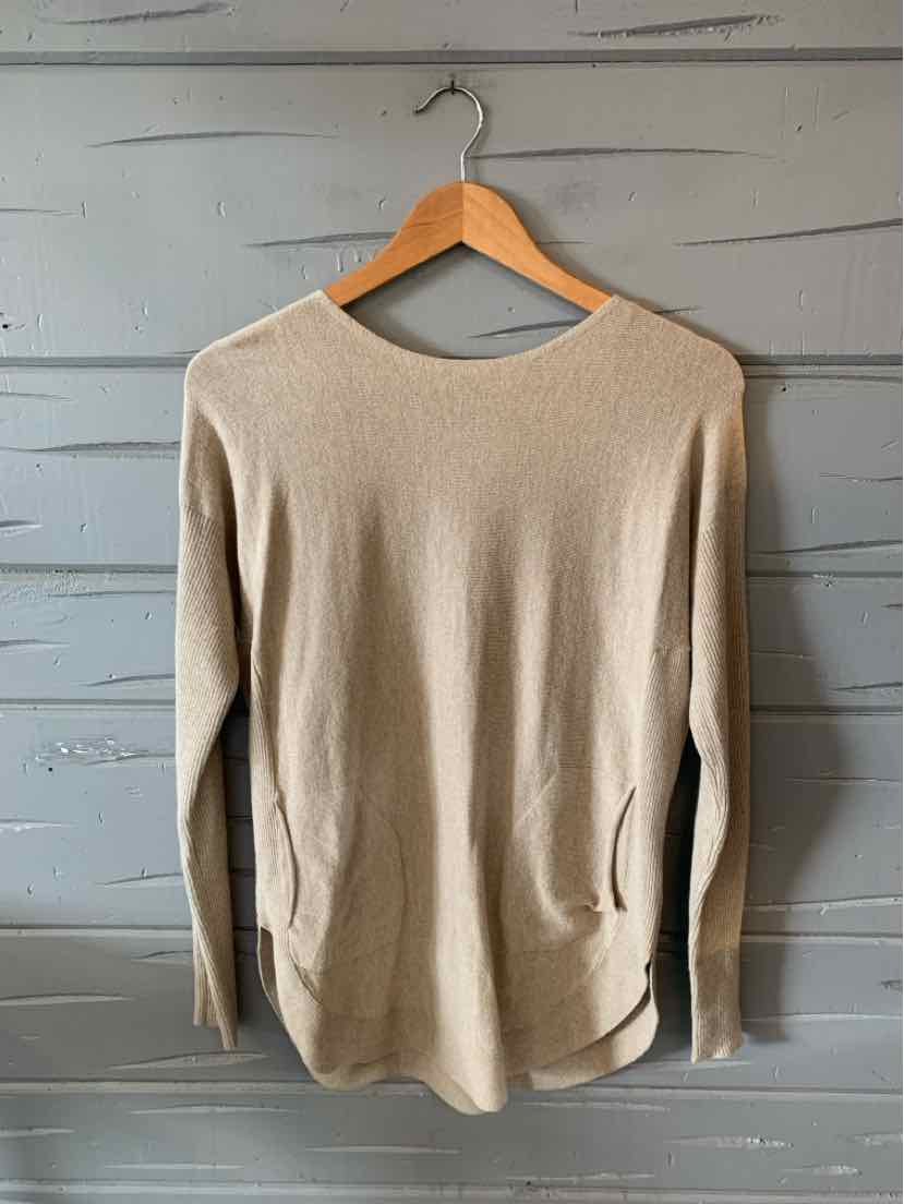 Tan long-sleeve knit sweater with a crew neckline and relaxed fit hanging on wooden hanger.
