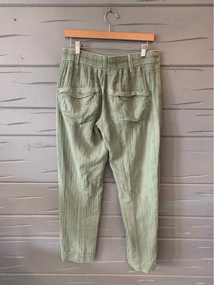 Light green high-waist pants with elastic waistband and two back patch pockets hanging on wooden hanger.