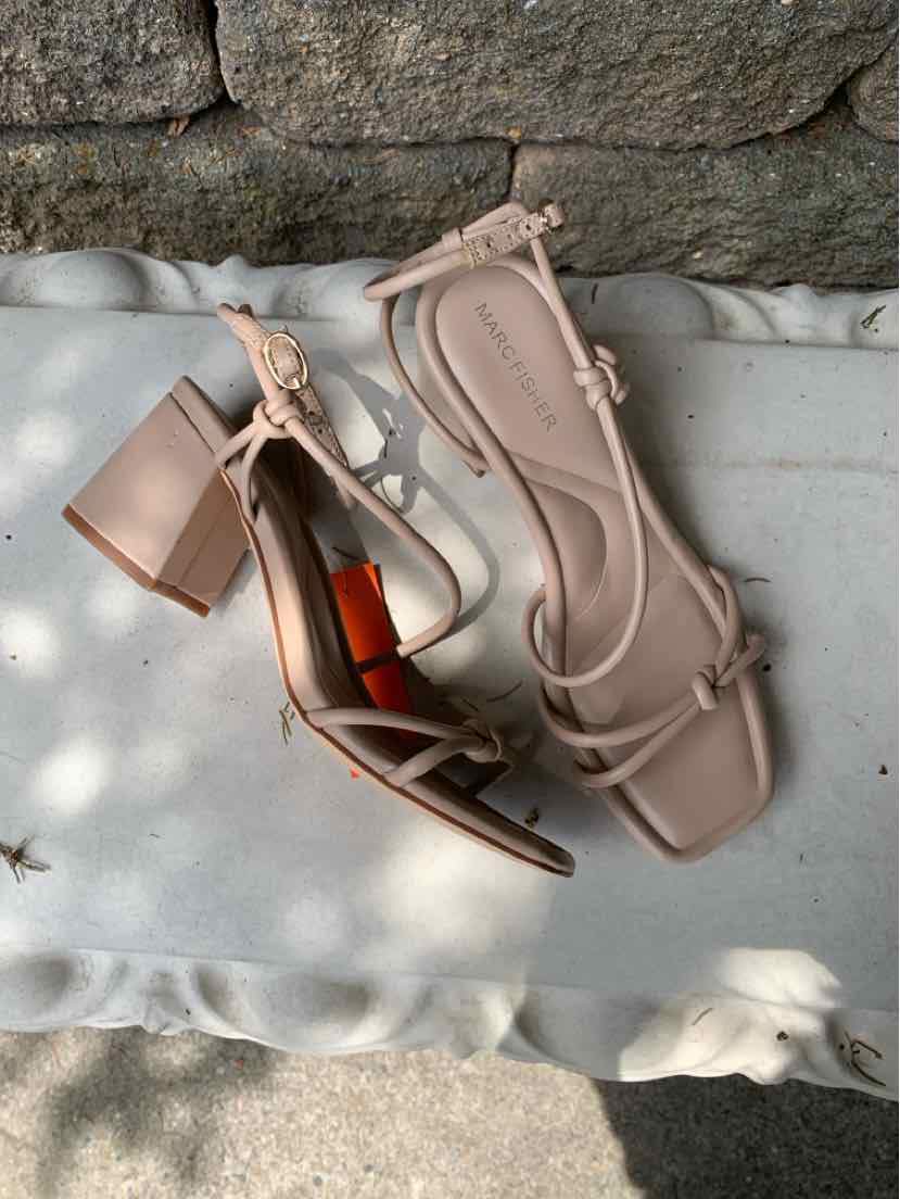 Beige block heel sandal with square toe, ankle strap, and tie detail.