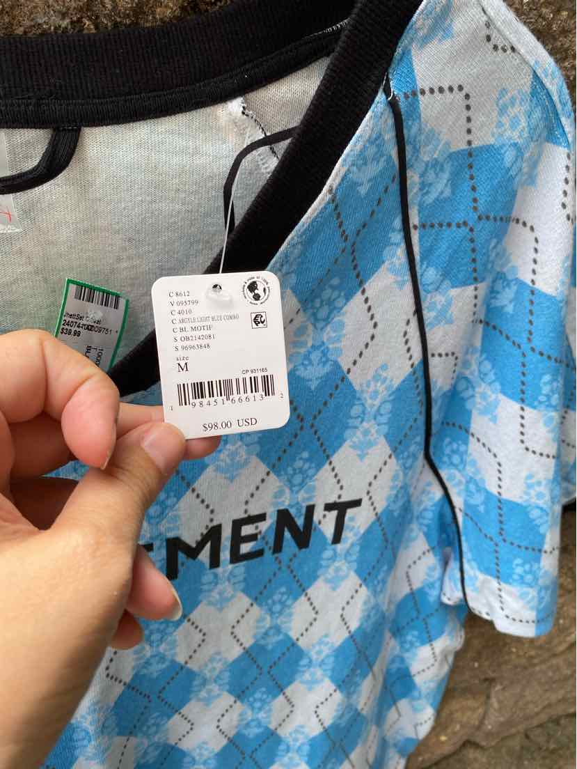 Blue and white argyle patterned short-sleeve top with black trim and printed text detail.