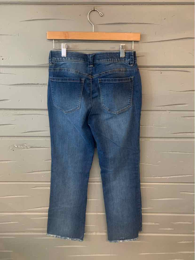 Blue denim jeans with frayed hems and back pockets on wooden hanger.