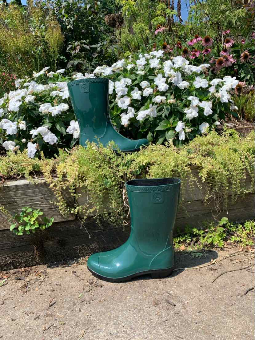 Glossy dark green rubber rain boots with mid-calf height and rounded toes, size 6, displayed outdoors.