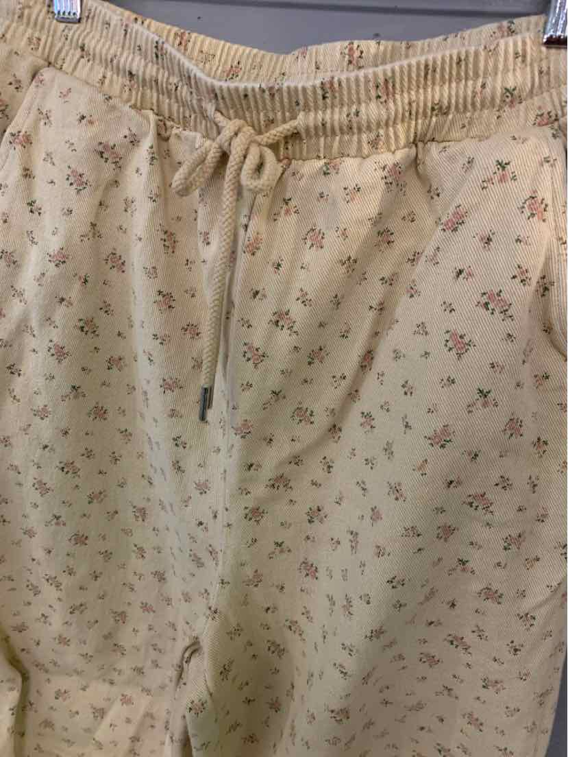 Beige drawstring pants with small floral prints and elastic waistband.