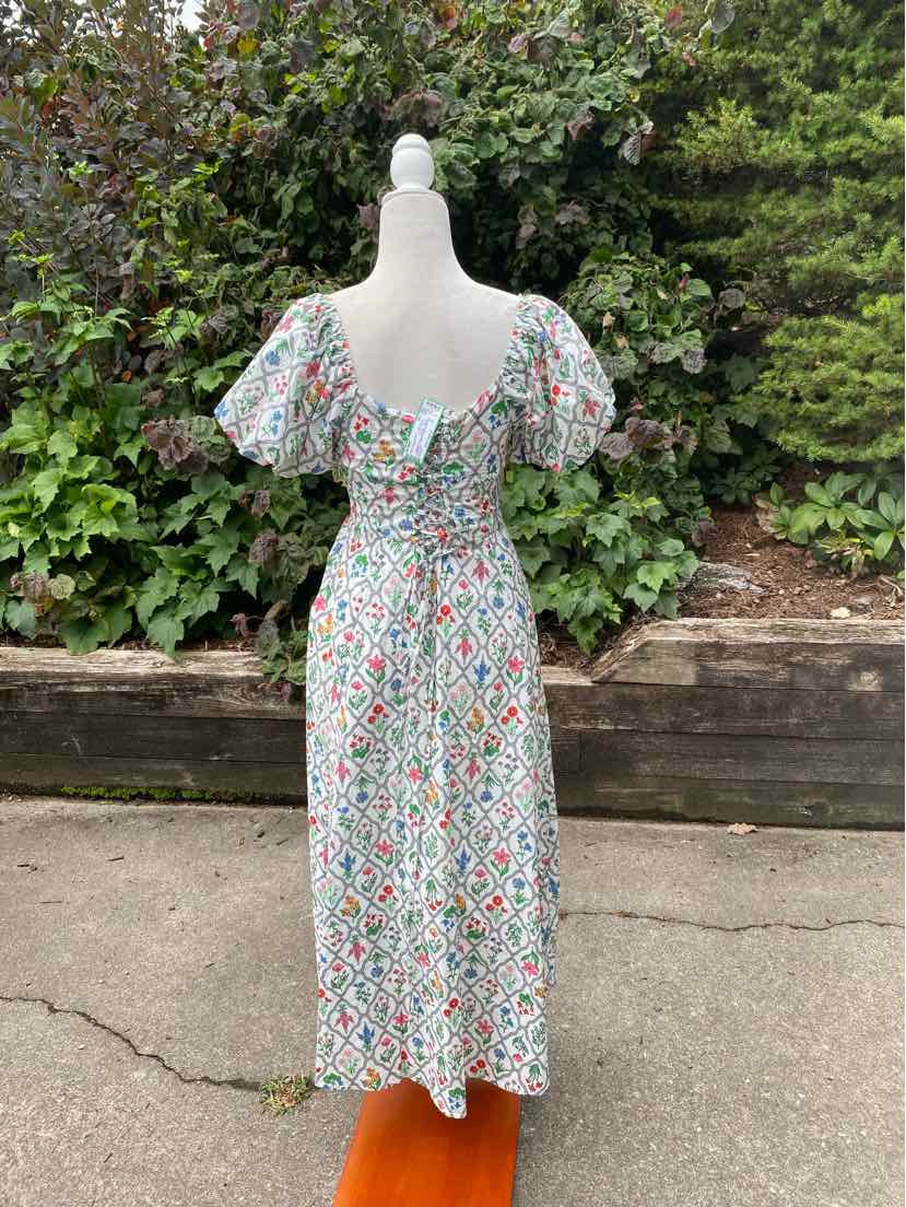 White midi dress with colorful floral print, puff sleeves, square neckline, and fitted waist.