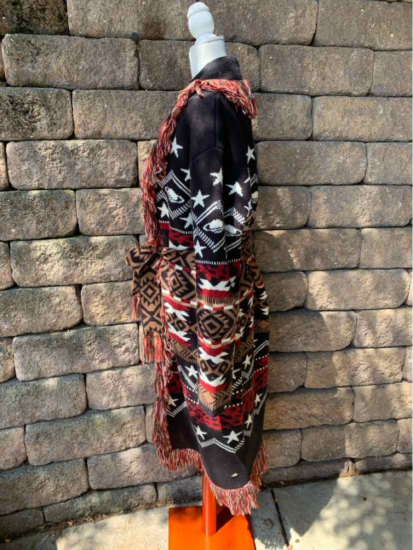 Black and red Southwest-patterned scarf with fringed edges, draped on white mannequin against stone wall.