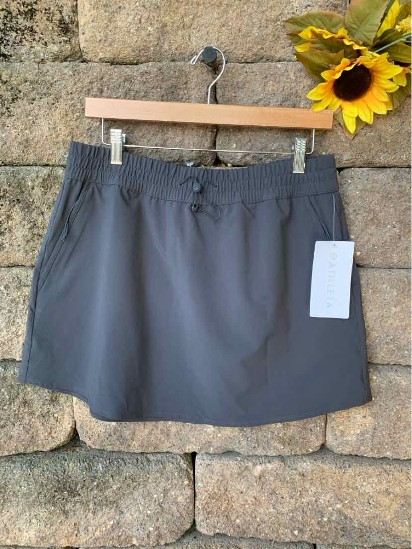 Dark gray athletic skirt with elastic waistband and front pockets hanging on wooden hanger.