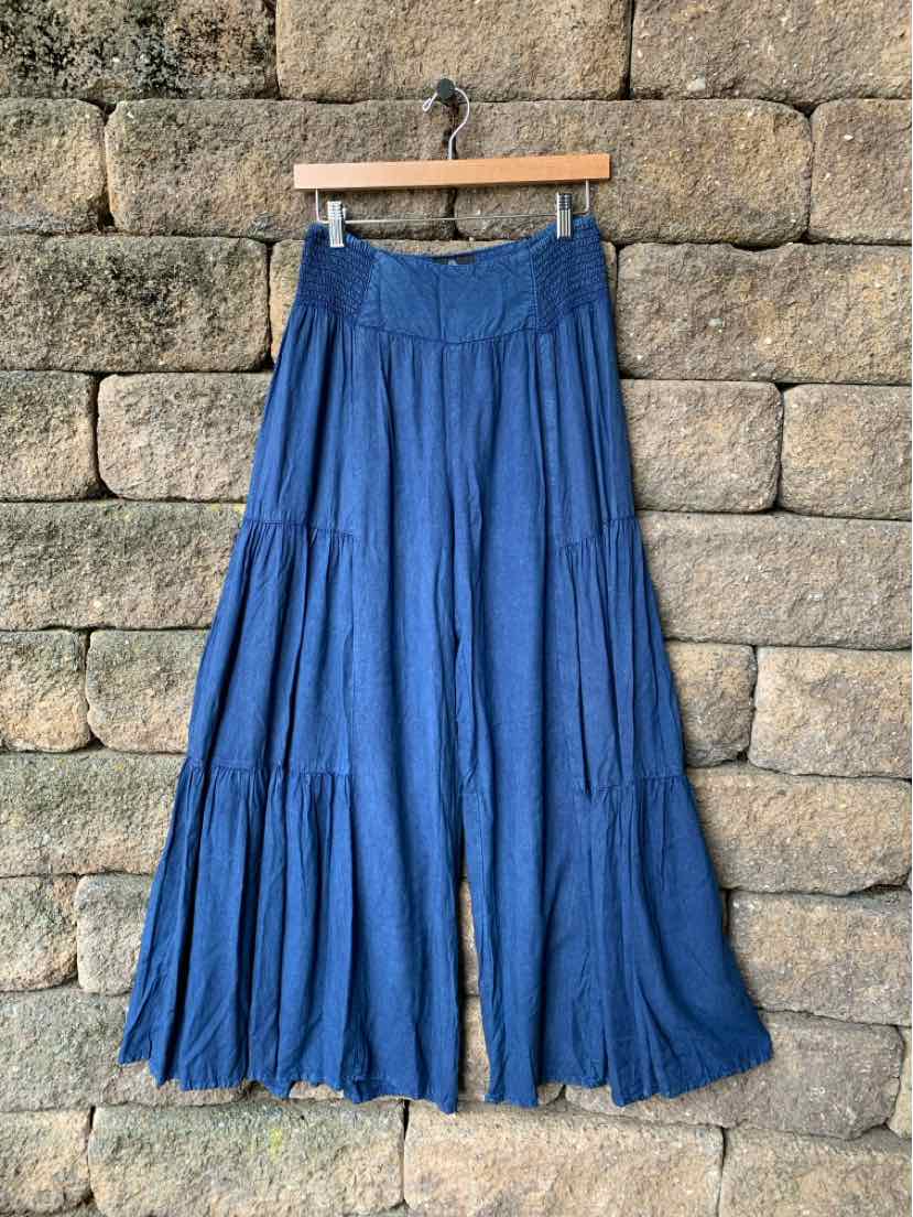Flowy blue maxi skirt with tiered panels and an elastic waistband hanging on wooden hanger.
