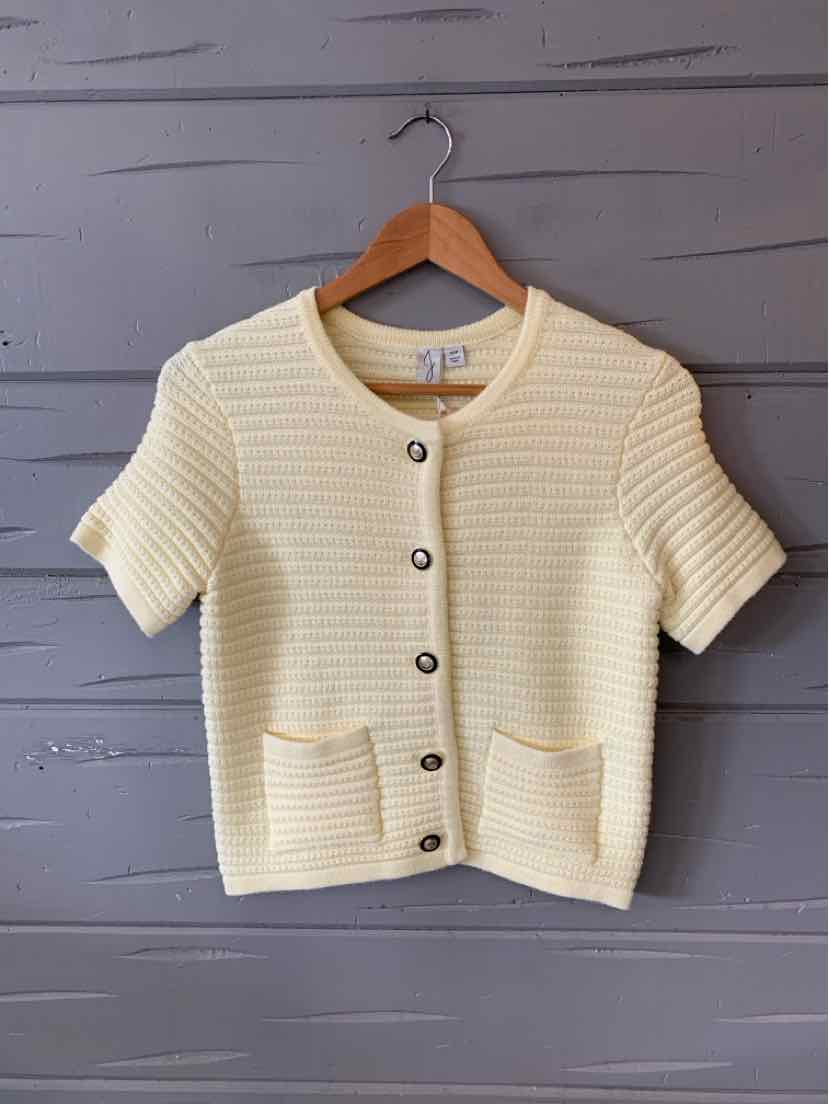 Cream short-sleeve knit cardigan with ribbed texture, round neckline, front buttons, and two front pockets.