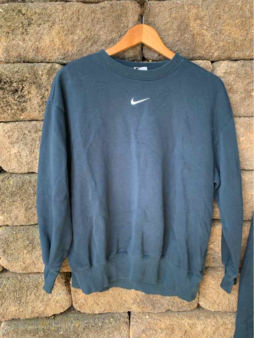 Black Nike sweatshirt with white swoosh logo on front, crewneck, long sleeves, ribbed cuffs and hem.