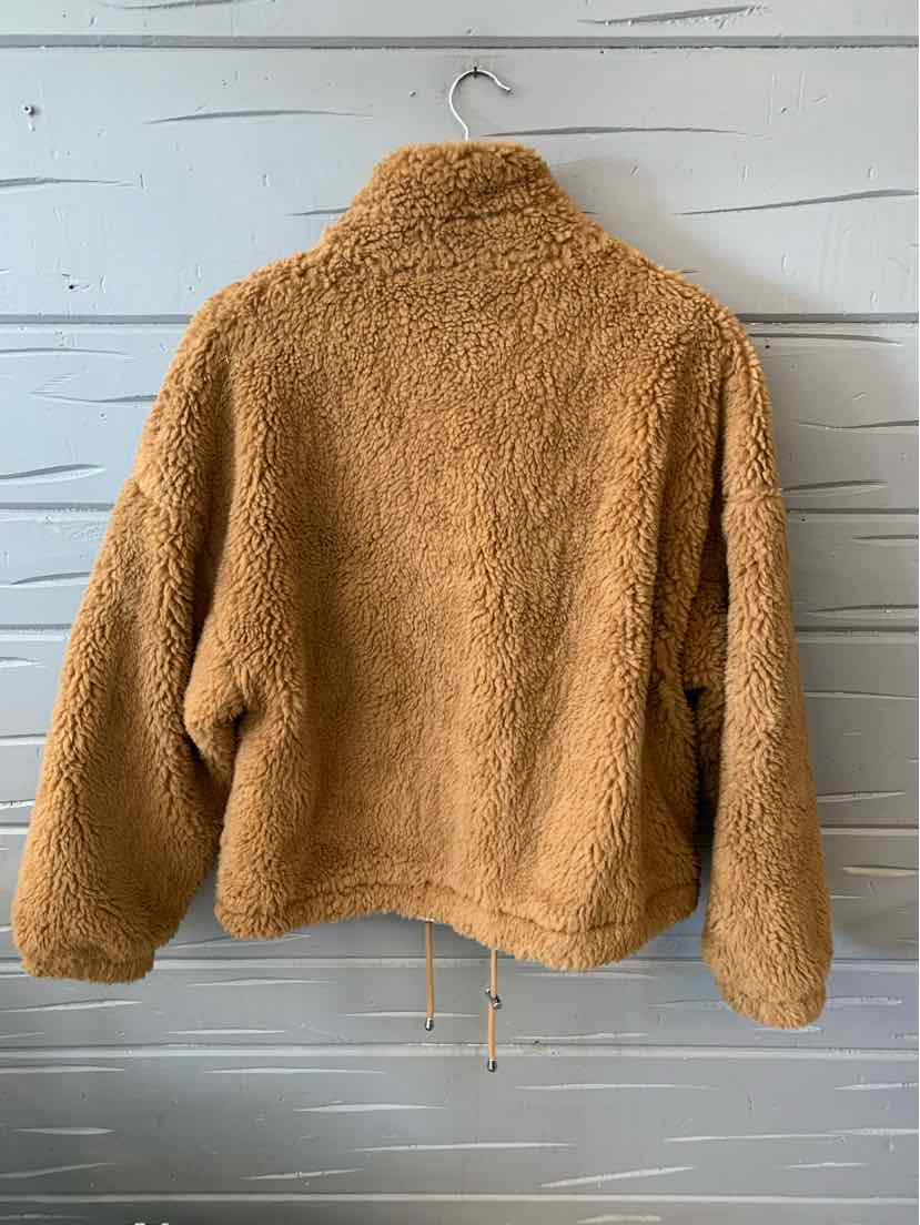Tan plush sherpa jacket with loose fit and high collar hanging on wooden hanger.