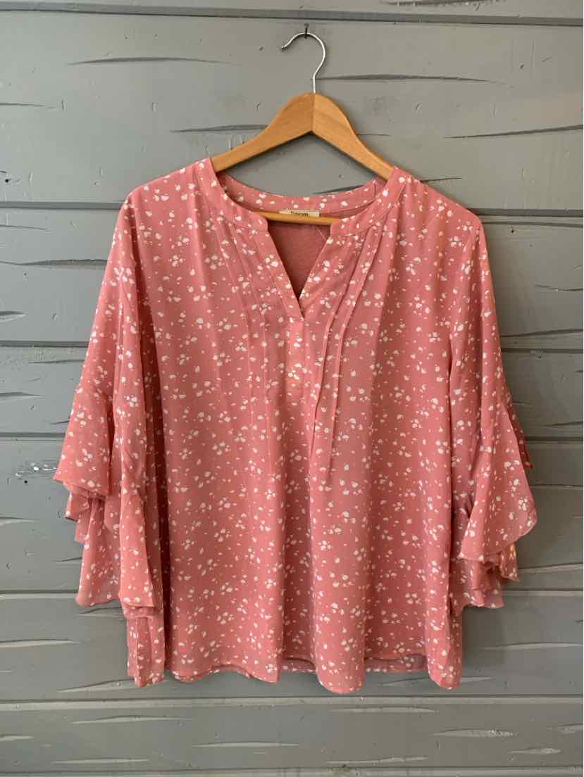 Pink oversized blouse with white floral pattern, V-neckline, and tiered ruffle sleeves.