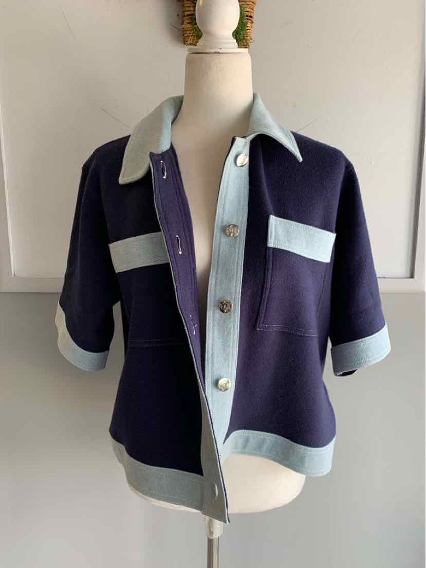 Navy blue short-sleeve cardigan with light blue collar, cuffs, and pocket accents, button front closure.