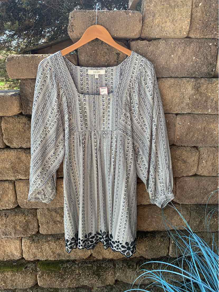 Light melon blouse with puffed long sleeves and black floral embroidery along the hem.
