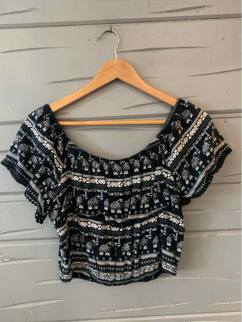 Black off-shoulder crop top with white elephant and geometric print on wooden hanger.