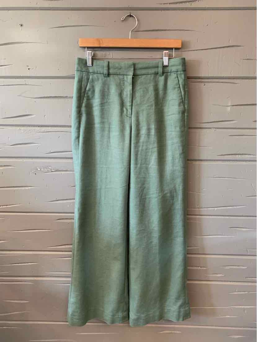 Light green high-waisted wide-leg trousers with belt loops hanging on wooden hanger.