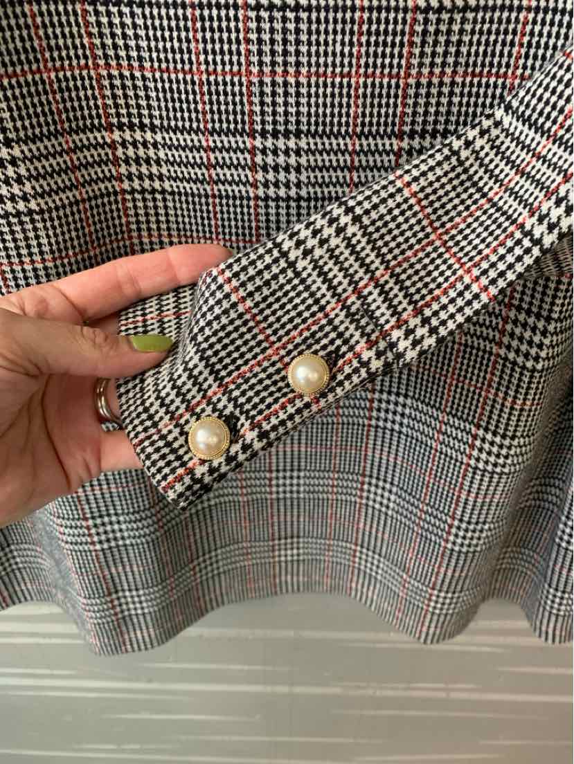 Black and white houndstooth fabric with thin red stripes, pearl button details on cuff.