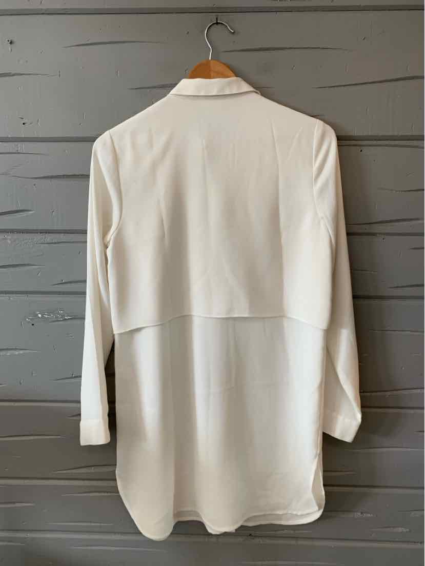 White long-sleeve blouse with extended back hem and relaxed fit on wooden hanger.