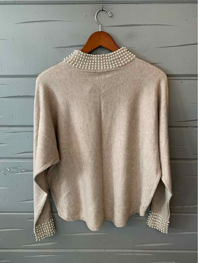 Beige knit sweater with a relaxed fit, ribbed cuffs and hem, and a white beaded collar.