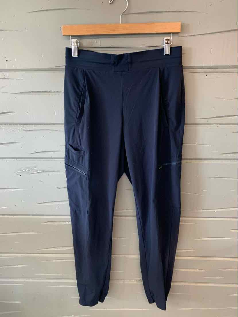 Black tapered athletic pants with side pockets and elastic cuffs on wooden hanger.