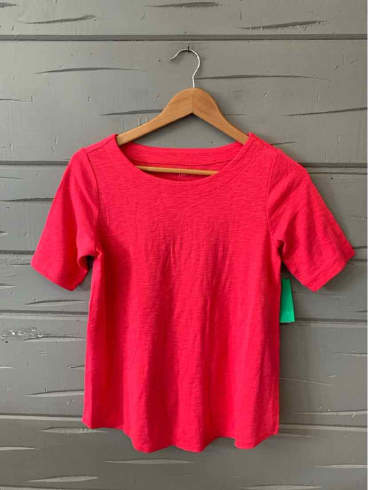 Bright pink short-sleeve knit top with scoop neckline on wooden hanger.