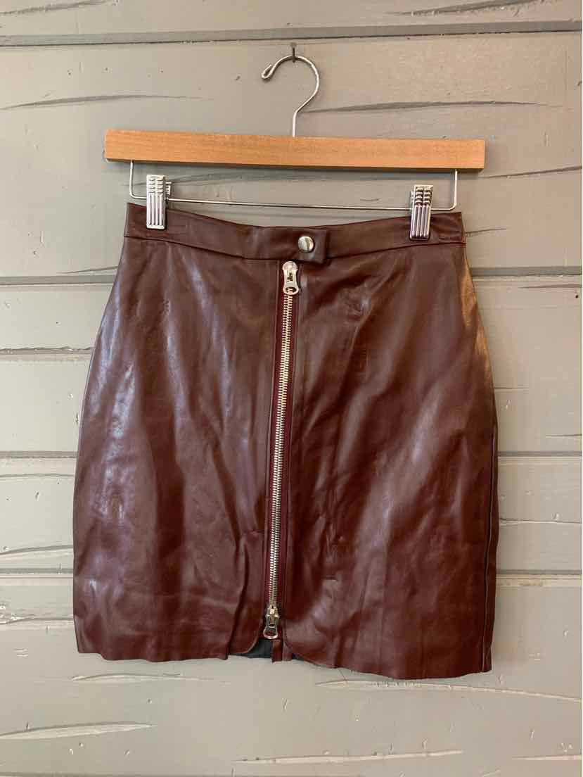 Burgundy faux leather mini skirt with front zipper and button closure hanging on wooden hanger.