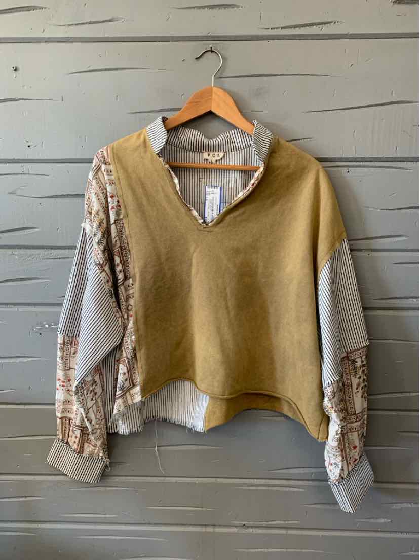 Olive green knit V-neck vest layered over a white blouse with patterned sleeves and hem.