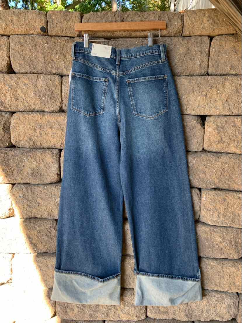 Wide-leg blue denim jeans with rolled cuffs, belt loops, front pockets, and a button closure.