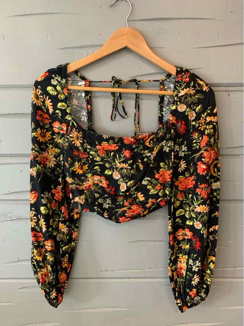 Black floral crop top with long puffed sleeves and square neckline on wooden hanger.